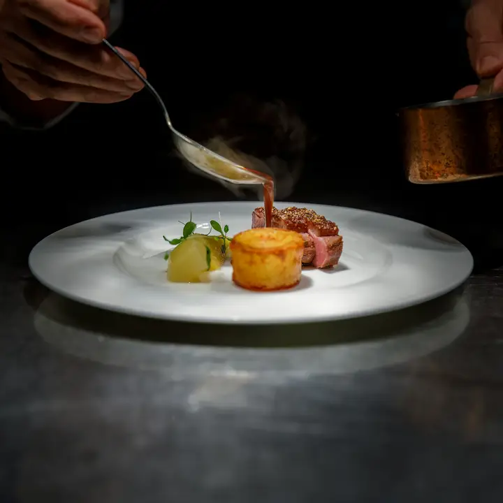 Una mano napa con su jugo un plato de carne