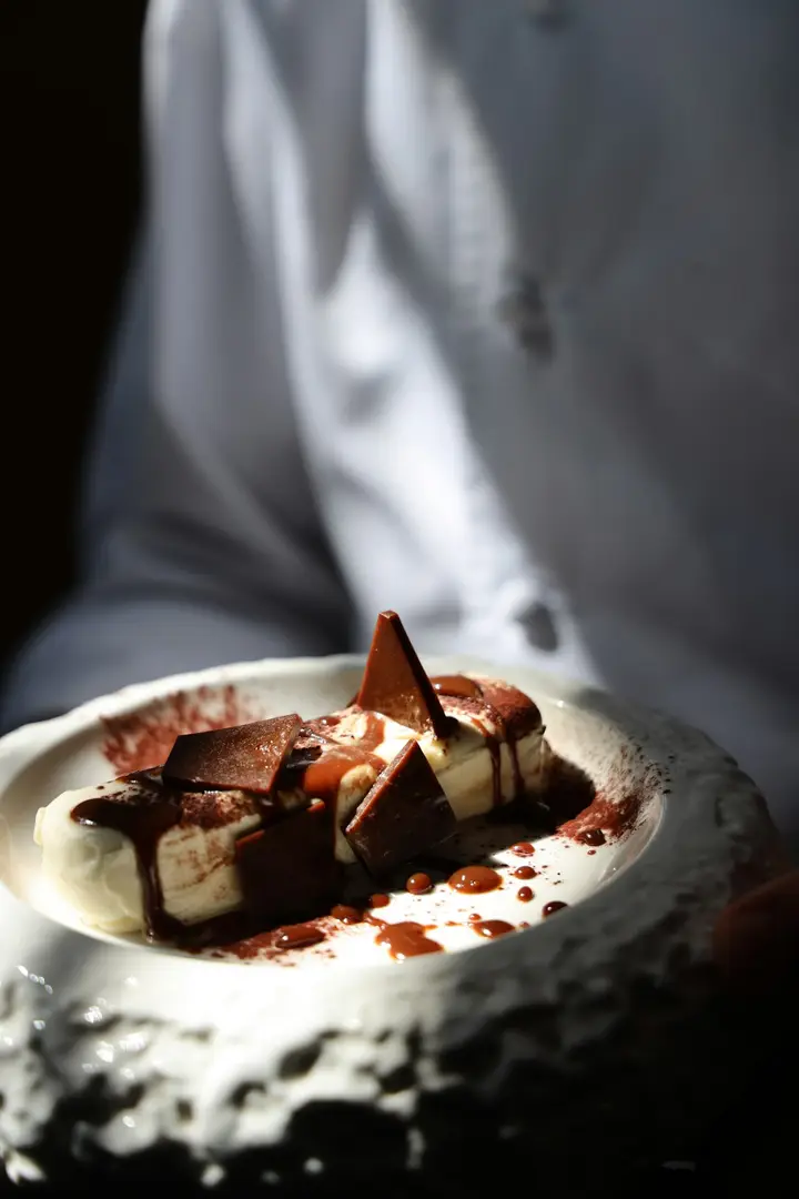 Postre de chocolate en un cuenco de cerámica sostenido entre las manos