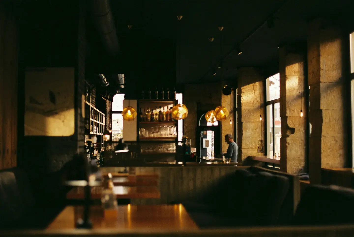 Comedor en penumbra con mesas de madera y luz cálida