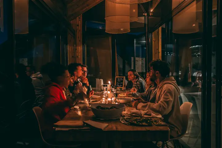 Grupo cenando a la luz de las velas en un comedor en penumbra