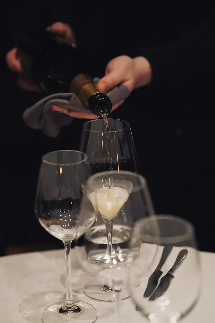 Vino servido en copas sobre una mesa vestida de blanco