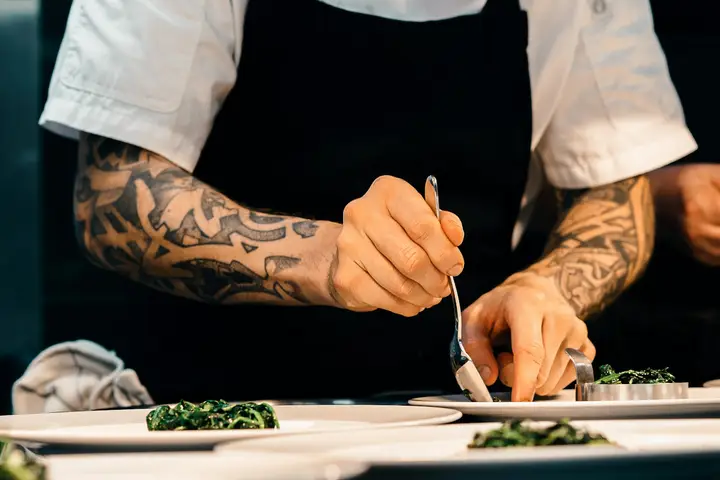 Manos tatuadas que emplatan con una cuchara
